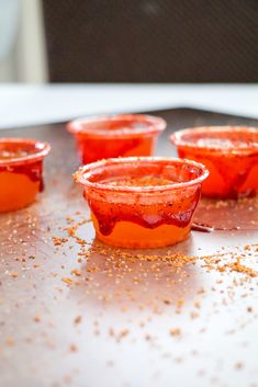 small cups filled with red liquid sitting on top of a counter covered in gold flakes