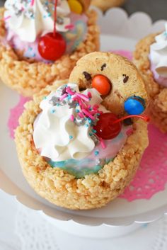 three cookies with icing, sprinkles and candy are on a plate