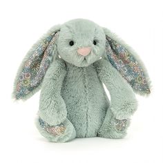 a light blue stuffed rabbit with floral designs on its ears and tail, sitting against a white background