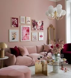 a living room with pink walls and pictures on the wall