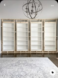 an empty room with white bookcases and a chandelier