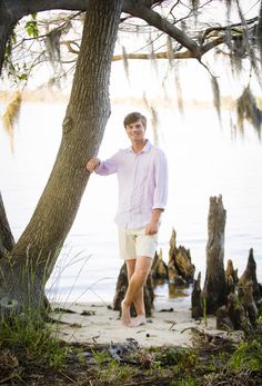 a man standing next to a tree near the water