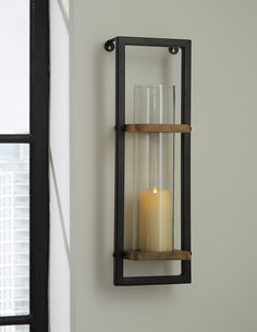 a candle that is sitting on top of a shelf next to a wall mounted light