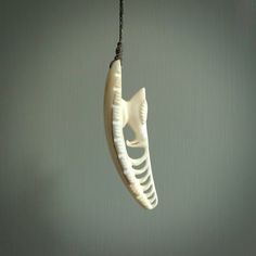 a white fish bone hanging from a black cord