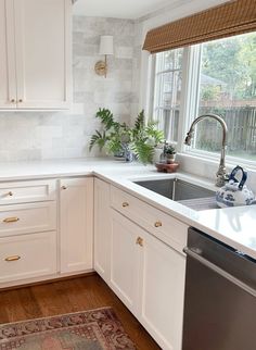 a kitchen with white cabinets and an area rug in front of the sink that is next to the dishwasher