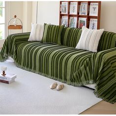 a living room with a green striped couch and pillows on the floor next to a white rug