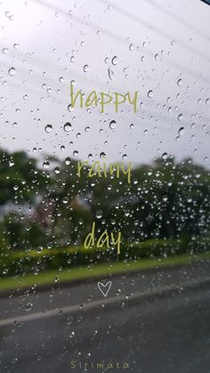 the words happy rainy day are written in green ink on a wet window pane