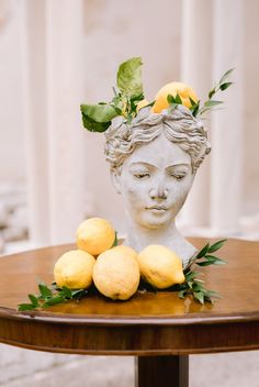 a statue with lemons on top of it sitting on a table next to some leaves