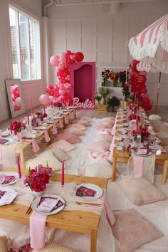 a table set up for a party with pink and white decorations, plates, napkins and balloons