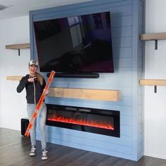 a woman standing in front of a flat screen tv holding an orange fire extinguisher