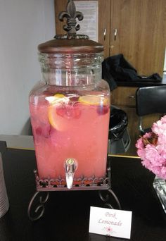 a pink lemonade drink in a glass jar on a table with flowers and a name tag