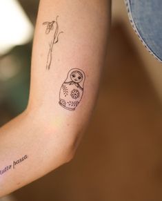 a small tattoo on the arm of a woman with a flower and a doll in it