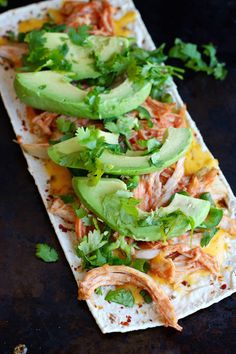 an enchilada is topped with avocado and cilantro