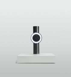 a black and white object sitting on top of a white table next to a gray wall