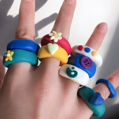 a person's hand with five different rings on it, all decorated in various shapes and sizes