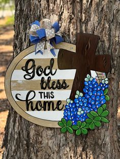 a wooden sign that says, god bless this home with blue flowers and a cross on it