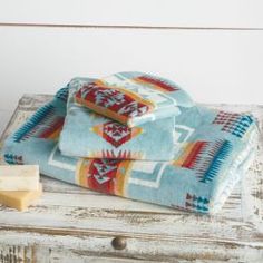 towels and soap on an old wooden table in front of a white wall with wood planks