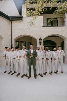 a group of men standing next to each other in front of a white brick building