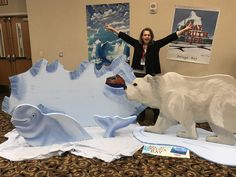 a woman standing next to a statue of a polar bear and an ice floer