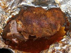 a piece of meat sitting on top of tin foil covered in sauce and seasoning