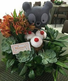 a teddy bear sitting on top of a basket filled with flowers and plants next to a sign