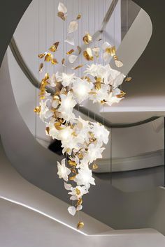 a chandelier with white flowers hanging from it's sides in a room