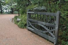 a wooden gate in the middle of a dirt path