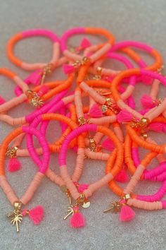 an assortment of orange and pink bracelets with tassels on the ends,