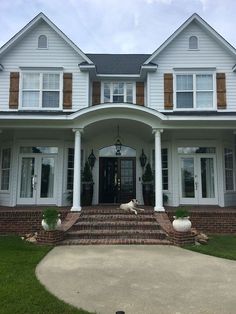 a large white house with two dogs laying on the front porch and steps leading up to it