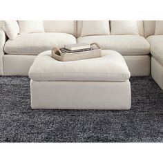 a white couch and ottoman in a living room with carpeted flooring on the ground