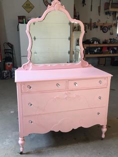 a pink dresser with a mirror on top of it