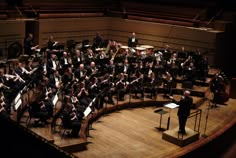 conductor and orchestra members on stage in large auditorium