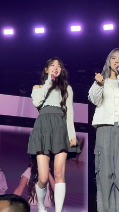 two girls are performing on stage with microphones