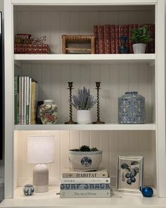 a white book shelf filled with books and vases