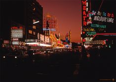 a city street filled with lots of neon signs and tall buildings in the night time