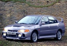 a silver car parked in front of a stone wall