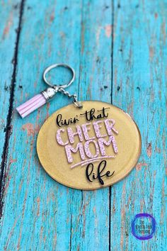 a keychain with the words give that cheer mom life written in pink on it