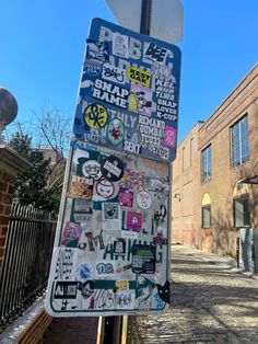 a street sign covered in stickers on the side of a road next to a brick building