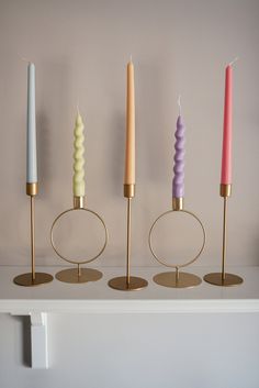 five candles are lined up on a shelf with one candle in the middle and another burning