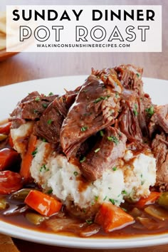 a white plate topped with meat and potatoes covered in gravy on top of a wooden table