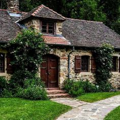 an old stone house with ivy growing on the roof and windows, along with a path leading to it