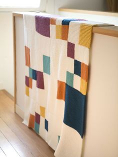 a kitchen counter with a multicolored quilt hanging from it's back end