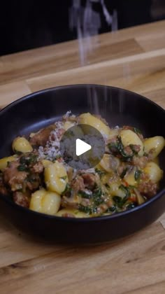 a bowl filled with pasta and meat on top of a wooden table