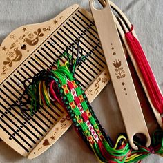 two wooden combs with different colored thread on top of each other next to a pair of scissors