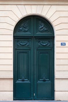 an ornately decorated green door on a beige building