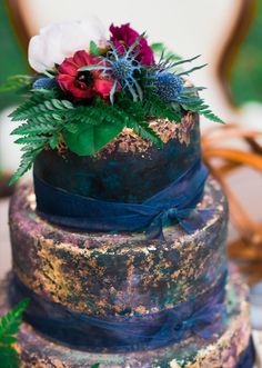 a multi - tiered cake decorated with flowers and greenery