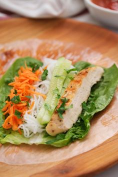 a wooden plate topped with lettuce and chicken