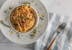 a white plate topped with pasta next to a fork