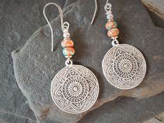 Bohemian Earrings with Mandala Dangle Boho style earrings with mandala charm and glass beads. The glass beads have beachy mixed colors of corals, blues, pinks and cream. Every bead is different, but just as beautiful.  Perfect earrings for those looking for a bohemian, beachy vibe. Very light weight Total hanging length is 2 1/2 inches. The mandala charm is the size of a quarter Artisan Nickel Free Beaded Earrings For Festivals, Bohemian Single Drop Earring, Bohemian Round Earrings For The Beach, Handmade Sterling Silver Bohemian Earrings, Handmade Bohemian Sterling Silver Earrings, Bohemian Dangle Earrings For Jewelry Making, Bohemian Adjustable Teardrop Earrings, Handmade Silver Bohemian Earrings, Handmade Bohemian Drop Earrings