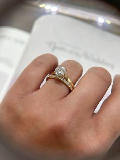 a woman's hand with a ring on it and a book in the background